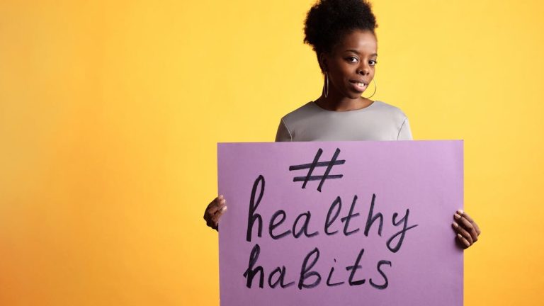 Portrait of a woman holding a healthy habits sign, set against a vibrant yellow background.